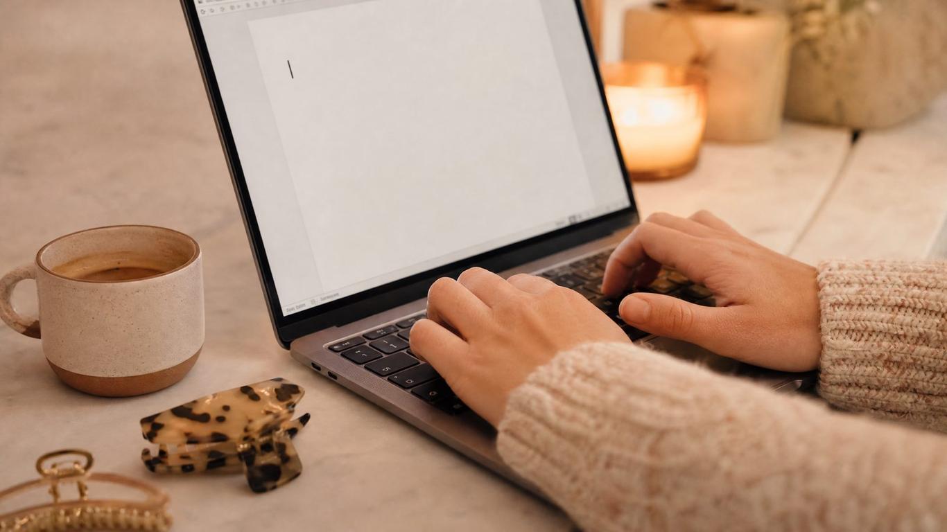 A marketer typing salon ad copy on a laptop next to an Ads Manager dashboard